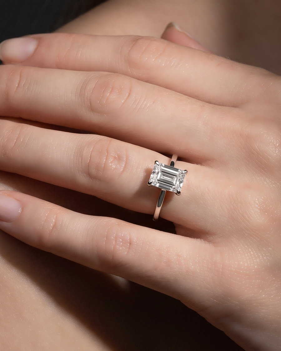 Mão com anel solitário de diamante de lapidação Emerald